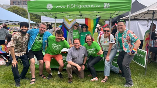 Green volunteers pose for a photo with Mike Schreiner and Aislinn Clancy at the Green booth at tri-Pride.